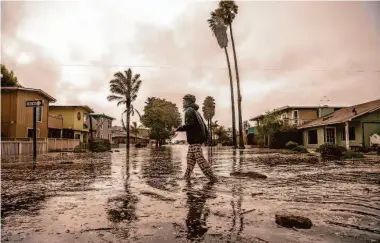  ?? Gabrielle Lurie/The Chronicle ?? Mike Panero wades through water Thursday to help neighbors on Aptos Beach Drive in Santa Cruz County.