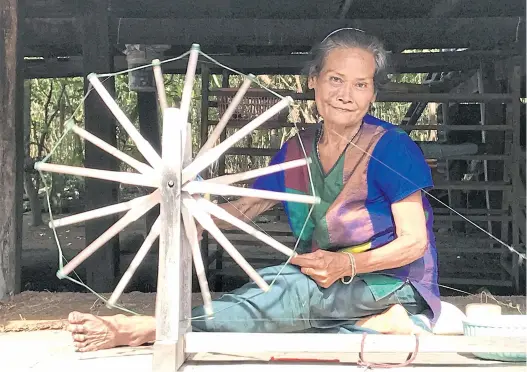  ??  ?? Saling Kumram uses a spinning tool to soften raw silk yarn.