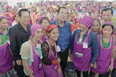  ?? — AFP ?? Cambodian Prime Minister Hun Sen (C) seen with workers at a factory compound on the outskirts of Phnom Penh on Wednesday.