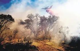  ?? Noah Berger / Associated Press ?? An air tanker drops retardant on the Olinda Fire burning in Anderson ( Shasta County).