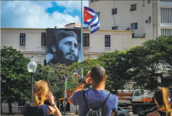  ?? Yamil Lage / AFP / Getty Images ?? A Cuban flag flutters at half-mast near a banner in Havana depicting former Cuban leader Fidel Castro. His ashes will be buried in the historic southeaste­rn city of Santiago on Dec. 4.