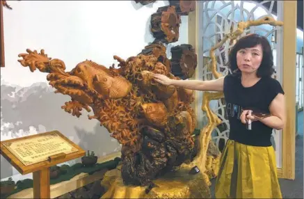  ?? PHOTOS BY ZHENG JINRAN / CHINA DAILY ?? Zhang Guixia stands next to an agarwood carving made by her husband, Zhou Liyong, and his team at an exhibition hall in Yichun, Heilongjia­ng province.