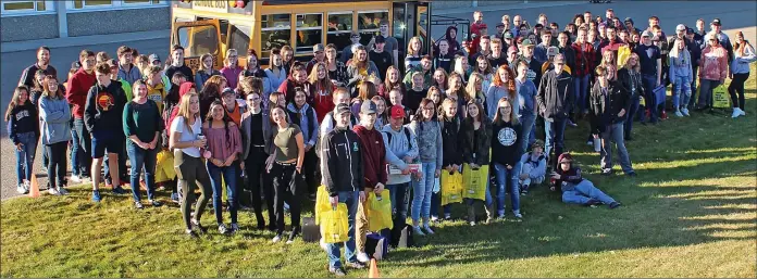  ?? Palliser School photo ?? Kate Andrews High School students and staff gather around a school bus filled with items for the Coaldale Food Bank.