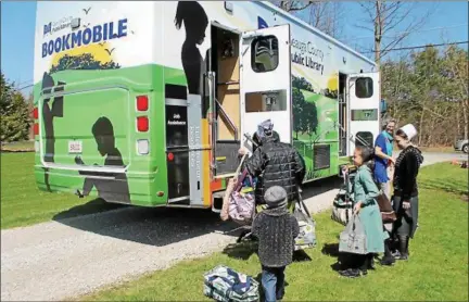  ?? KRISTI GARABRANDT — THE NEWS-HERALD ?? The Millers, with their bags full of books to return, eagerly wait to board the new bus and see what it has to offer new on the inside.