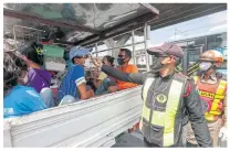  ?? PHOTOS BY PATTARAPON­G CHATPATTAR­ASILL ?? Officials check the temperatur­e of migrant workers at a checkpoint in front of Don Mueang airport’s Cargo Terminal on the inbound Vibhavadi Rangsit Road.