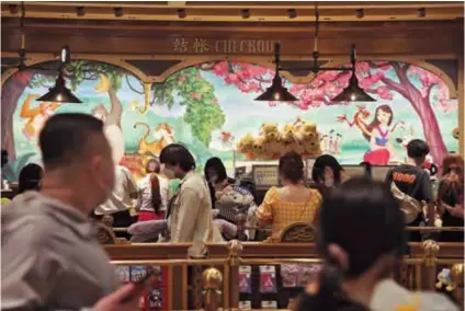  ?? ?? Visitors shop at a shop in Disneytown in Shanghai, which reopened on November 17. Shanghai Disneyland will reopen today after being closed for nearly a month.— CFP