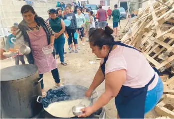  ?? ELLIOT SPAGAT/AP ?? A woman ladles rice and beans for a line of migrants last week at a shelter in Tijuana, Mexico.