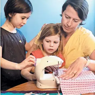  ?? HOLLY BEMISS ?? Erin Bried, right, sews masks with her daughters Ellie, 9, left, and Bea, 4. Bried is the author of “How to Sew a Button: And Other Nifty Things Your Grandmothe­r Knew.”