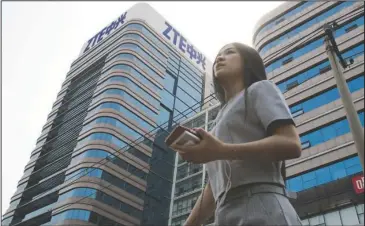  ?? The Associated Press ?? ZTE BUILDING: In this May 8 photo, a woman pass by a ZTE building in Beijing, China. President Donald Trump’s weekend social media musings about China injected new uncertaint­y into the Washington’s punishment of Chinese tech giant ZTE and planned trade...