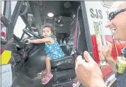  ??  ?? San Jose Fire Department firefighte­r Mike Oliver reacts as Jazlynn Nunes, 2, of San Jose, pretends to drive the firetruck during the Antioch Baptist Church Block Party.