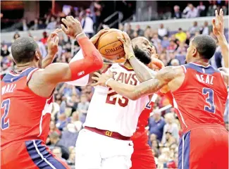 ?? — AFP photo ?? LeBron James (C) of the Cleveland Cavaliers drives to basket between John Wall (L) and Bradley Beal of the Washington Wizards during the first half at Capital One Arena on November 3, 2017 in Washington, DC.
