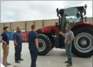 ?? SUBMITTED ?? Wellington Implement GM Tom Stannard gives an overview of the tractor to IEM instructor Mason Bremke and students from left Nicholas Borlaug (North Ridgeville) and Aidan Marang (Keystone)