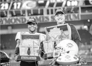  ?? WILLIE J. ALLEN JR./ORLANDO SENTINEL ?? UCF receiver Ryan O’Keefe holds his MVP trophy and head coach Gus Malzahn holds the winning Gasparilla Bowl trophy after last week’s win in Tampa.