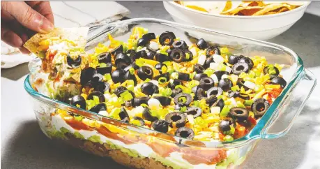  ?? REY LOPEZ/FOR THE WASHINGTON POST ?? It's simple to modify a standard seven-layer dip with lettuce, pickled jalapeños, corn kernels or ground meat.