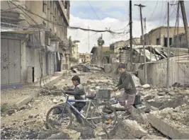  ??  ?? Recuperan. Niños iraquíes caminan en una calle destruida en un barrio retomado recienteme­nte por fuerzas gubernamen­tales en Mosul.