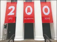  ??  ?? A worker adjusts a banner celebratin­g Alabama’s bicentenni­al outside the Department of Archives and History.