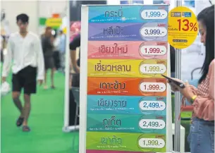  ?? SOMCHAI POOMLARD ?? A poster displays packages available at Thai Teaw Thai. The travel fair expects 200,000 local visitors this year.