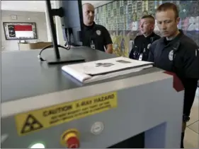  ??  ?? In this April 23, photo, General Assembly police officer Chase Honeycutt (right) demonstrat­es the new security equipment at the Legislativ­e Building in Raleigh, N.C. At the “People’s House” in North Carolina, lawmakers have long considered unfettered...