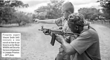  ??  ?? Firearms exper t Vincent Smith (left) instructs a new recruit on how to use firearms at the Nkwe Wildlife and Security Servicesin­Vaalwater in Limpopo Province. — AFP photo