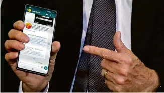  ??  ?? Jair Bolsonaro exibe no celular, em evento no Planalto, link para reportagem sobre o prejuízo das estatais em 2015, no governo petista, e o lucro delas em 2019, um ano após sua posse