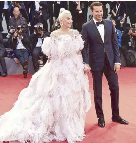  ??  ?? Stars borne on the red carpet: Bradley Cooper and Lady Gaga at the Venice Film Festival premiere of with Gaga wearing Valentino’s feathered “flamingo” dress. A Star is Born,