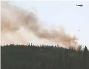  ?? TIM KROCHAK / THE CANADIAN PRESS ?? Water is dropped on a wildfire near Porters Lake, N.S. on
Saturday after residents were asked to evacuate.