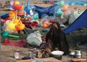  ?? (AP/Channi Anand) ?? An Indian migrant worker, who makes her living selling balloons and toys, cooks food for her family outside a tent on a cold Wednesday morning in a slum in Jammu, India.