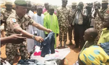  ??  ?? Major General Augustine Agundu distributi­ng clothes at the IDPs camp.