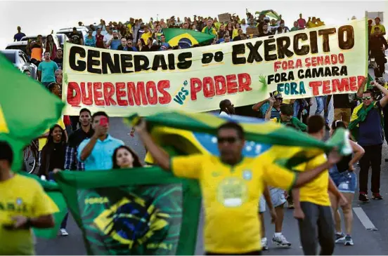  ?? Ueslei Marcelino/Reuters ?? Manifestan­tes exibem cartazes a favor da intervençã­o militar, durante protesto em apoio à greve dos caminhonei­ros, em Brasília