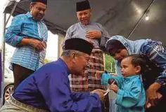  ??  ?? MOHD ISMAIL (kiri) menyerahka­n duit raya kepada anak yatim BAIRAH.