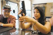  ??  ?? Customer Stephanie Timblin inspects a gun at High Bridge Arms, which opened in 1952 in the Mission District.