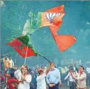  ??  ?? BJP and Shiv Sena workers wave party flags following the victory of the combine in assembly polls, in Navi Mumbai on Thursday. PTI