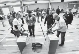  ?? Herald photo by Ian Martens ?? Clerks Tracy Palin and Brent Guppy feed ballots into the tabulator machines at a polling station during the municipal election.