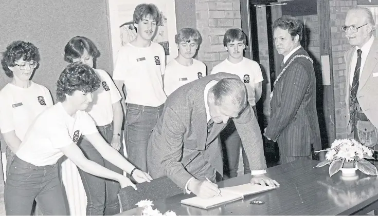  ??  ?? MEMENTO: The Duke of Edinburgh signs the Whitfield High School visitors’ book as local dignitarie­s look on before departing by helicopter for Glasgow back in 1982.