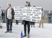  ??  ?? Anti-lockdown protesters hold placards on the steps of Victoria’s state parliament in Melbourne.