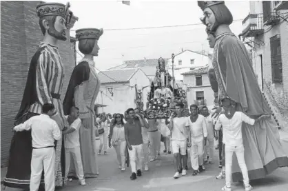  ??  ?? Los quintos del 2001 y de 1973 llevan al santo, ante el saludo de los gigantes.