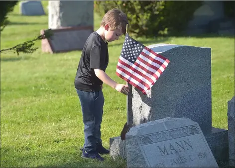  ?? PETE BANNAN - MEDIANEWS GROUP ?? Christian Ricciuti, 6, places a flag on a veteran’s grave at Arlington Cemetery Friday evening. His grandfathe­r is a member of the Upper Darby Marine Corps League.