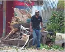  ?? MOISES CASTILLO/AP ?? A man walks past Costa Rica homes damaged by Tropical Storm Nate.