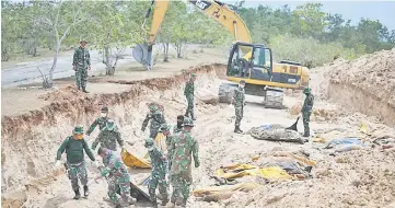  ?? — AFP photo ?? Indonesian soldiers bury quake victims in a mass grave in Poboya in Indonesia’s Central Sulawesi after an earthquake and tsunami hit the area.