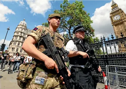  ?? PHOTO: REUTERS ?? A soldier and police officer walk past the Houses of Parliament in London as security patrols are increased following the Manchester bombing.