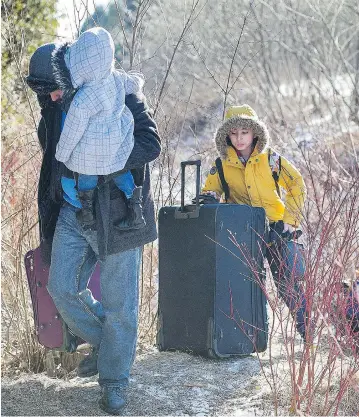  ?? GRAHAM HUGHES / THE CANADIAN PRESS ?? A family crosses the border in Hemmingfor­d, Que. Cabinet ministers are set for an in-depth discussion this week about the pressures being placed on the Liberal government by a rising number people seeking asylum in Canada.