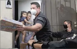  ?? Dania Maxwell Los Angeles Times ?? LAPD OFFICER Nick Ferara, center, with Officer Dan Brown, gets Victoria Taboada a donated game for her 3-year-old daughter, Victoria, in San Pedro.