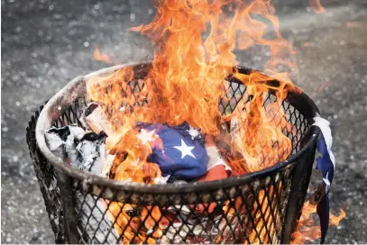  ?? ASHLEE REZIN/SUN-TIMES FILE ?? An American flag is retired by burning it in 2018. The U.S. Flag Code states that worn-out flags “should be destroyed in a dignified way, preferably by burning.”