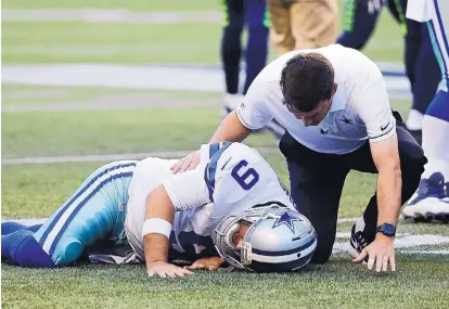  ?? ELAINE THOMPSON/ASSOCIATED PRESS ?? Dallas quarterbac­k Tony Romo (9) is tended to by a trainer after he went down in the first quarter of the Cowboys’ preseason game vs. Seattle on Thursday night.