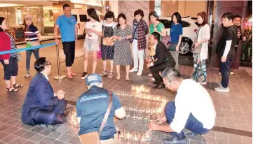  ??  ?? Lighting of candles in the shape of Earth Hour’s iconic 60+ symbol as guests inquire more about the movement.