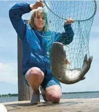  ?? LLOYD FOX/BALTIMORE SUN ?? Elisabeth Flavin holds a 25-inch blue catfish that she caught near the Concord Point Lighthouse in Havre de Grace in 2020. The fish are regarded as an invasive species in the Chesapeake Bay, where they may consume native striped bass, blue crab, shad, herring and Atlantic sturgeon.