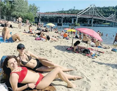  ?? Ageen Snasn ?? Julia y Valeria, dos amigas de 21 y 20 años, toman el sol en Kyiv en una playa a orillas del río Dniéper