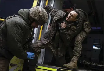  ?? EVGENIY MALOLETKA — THE ASSOCIATED PRESS ?? Ukrainian military medics help their wounded comrade to get out from an ambulance after arriving from the battlefiel­d to the field hospital near Bakhmut, Ukraine, Sunday.