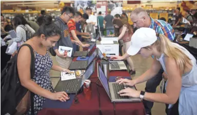  ?? PHOTOS BY PATRICK BREEN/THE REPUBLIC ?? Vrishti Shah (left) uses a computer to buy her cap and gown last week at an ASU campus bookstore in Tempe. Cap and gowns usually cost at least $60; Shah described the prices as "extremely expensive.”