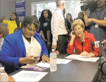  ?? Ben Nadler Associated Press ?? STACEY ABRAMS, left, a Democrat running for Georgia governor, and Sen. Elizabeth Warren (D-Mass.) reach out to voters. Abrams is the first black woman to win a major-party nomination for Georgia governor.